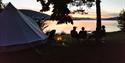 friends sitting in front of Glamping tent in the evening overlooking the water