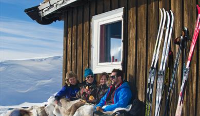 2 couples sitting in front of the cabin in winter enjoying the sun