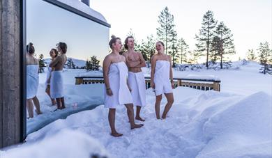 3 young people in the snow in front of the Panorama sauna