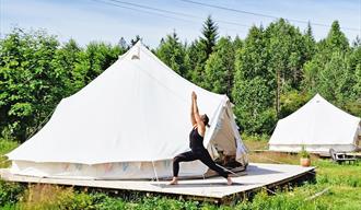 Turid from Yogalåva in Drangedal does yoga in front of a glamping tent