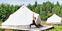 Turid fra Yogalåva i Drangedal driver med yoga foran en glampingtelt