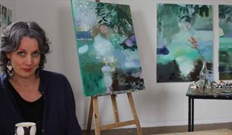 Kunstner Åsne Margrete Reiten med sine malerier i bakgrunnen
