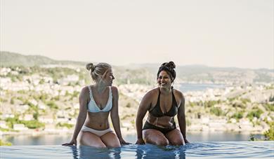 jenter som sitter på bassengkanten på utebassenget til Kragerø Resort