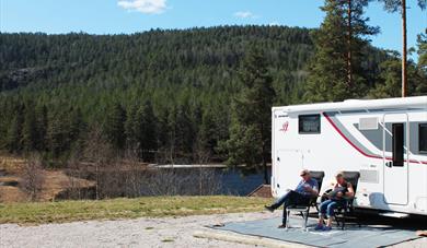 couple sitting in front of their motorhome in the motorhome parking at Drangedal bygdetun