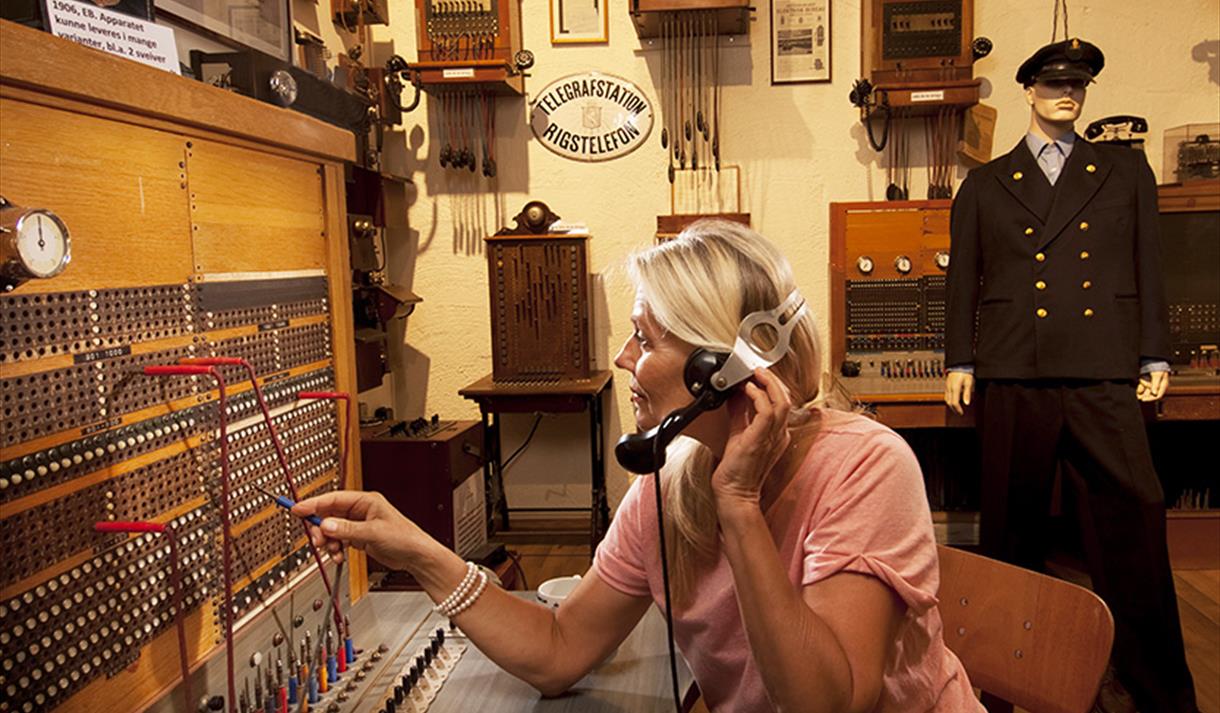 dame som sitter i en gammel telefonsentrale som utstilles på Z-museum i Nissedal