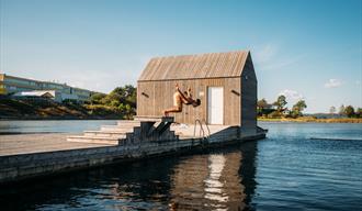 boy jumps from diving board in front of the floating sauna in Langesund