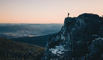 Mann på toppen av fjell med utsikt