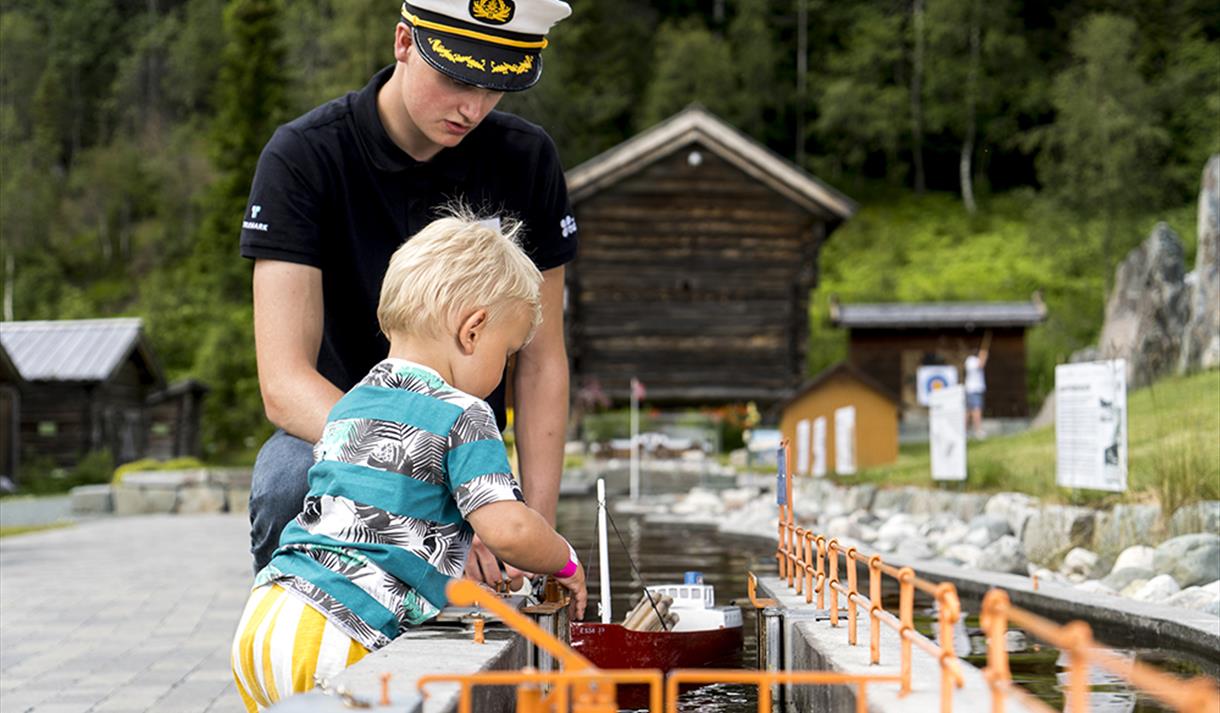liten gutt sluser en båt på miniatyrutgaven av telemarkskanalen på kanalparken på Vest-Telemark Museum i Eidsborg