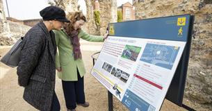 Two people reading information boards in Reading Abbey