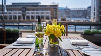 A table set up for dinner with a vase of flowers and a glass of wine.