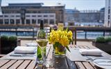 A table set up for dinner with a vase of flowers and a glass of wine.