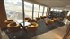 A view across the restaurant floor with yellow chairs and floor to ceiling windows with views across the city.