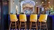 A blue coloured bar area with bright yellow bar stools.