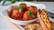 A bowl of meatballs and bread.