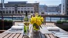 A table set up for dinner with a vase of flowers and a glass of wine.