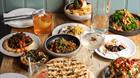 A table full of Mediterranean and Middle Eastern food with drinks.
