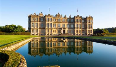 Longleat House in front of a lake with the house reflected in the water at Longleat