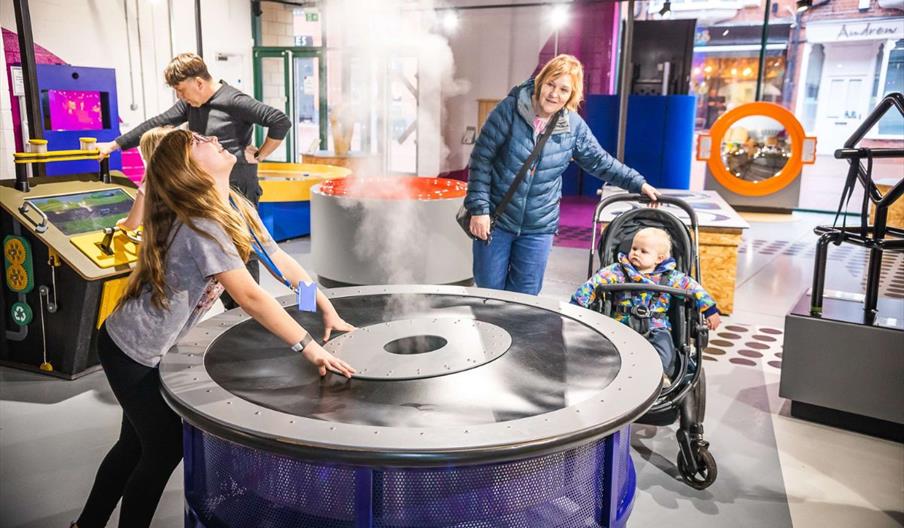 Parents and children interacting with exhibits at Xplore! Science Discovery Centre