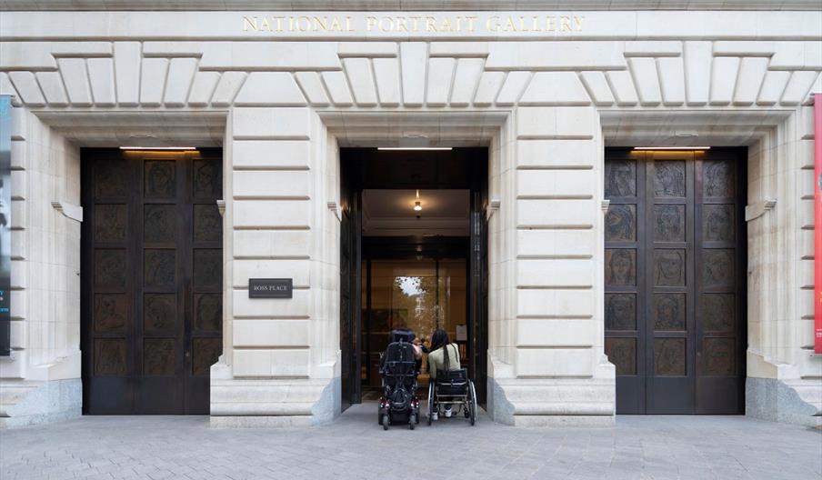 Two people in wheelchairs outside the main entrance of the National Portrait Gallery