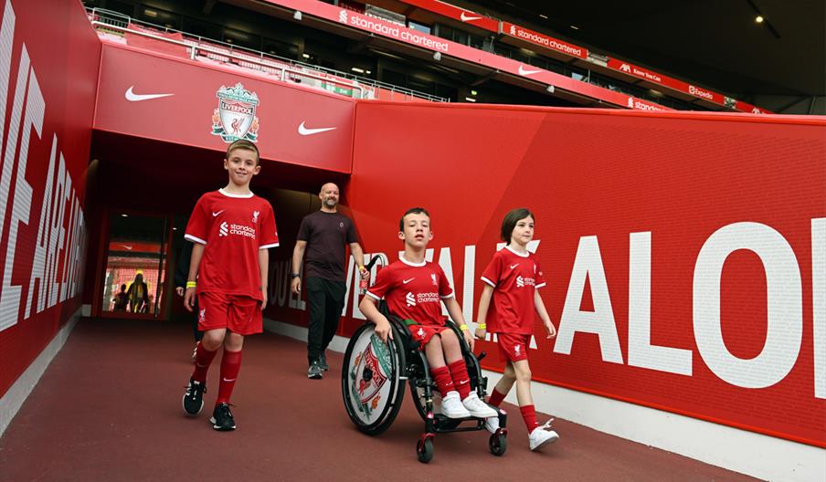 Three boys, one in a wheelchair going out onto the pitch LFC Stadium Tours & Experience