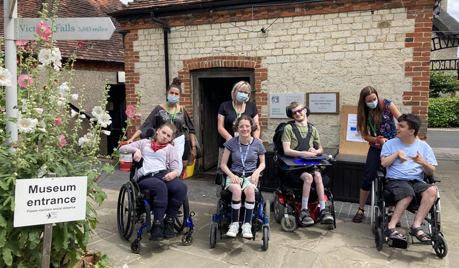 A group of people in wheelchairs at the entrance to Gilbert White's House