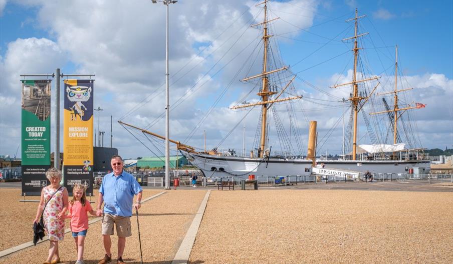 Family visiting The Historic Dockyard Chatham with a ship in the background