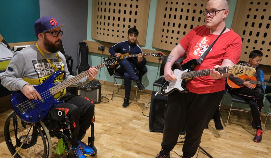 man in wheelchair playing guitar with a man standing playing guitar at Midlands Arts Centre