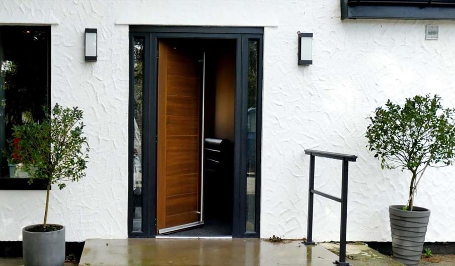 The front door of a white building, with two potted trees either side