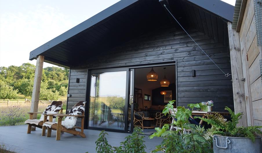 Front view of Oak Tree Cabin, with two chairs on the decking. The entrance to the cabin is flat.