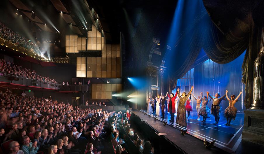 A performance taking place at Sadler’s Wells, with audience members applauding the actors on stage