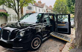 Taxi4Hire's black cab parked on the side of the road with the ramp out