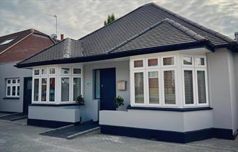 Entry to AbleStay, a grey bungalow style building with a wheelchair ramp leading up to the front door