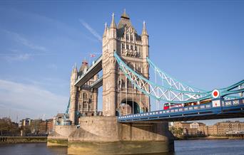 A red bus driving over Tower Bridge