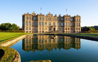 Longleat House in front of a lake with the house reflected in the water at Longleat