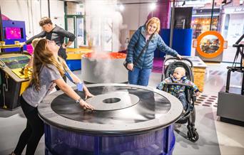 Parents and children interacting with exhibits at Xplore! Science Discovery Centre