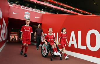 Three boys, one in a wheelchair going out onto the pitch LFC Stadium Tours & Experience