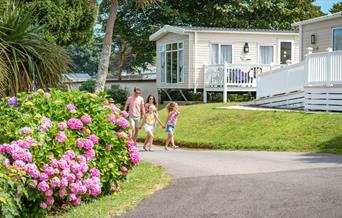 Family walking past the lodges at John Fowler Holiday Parks