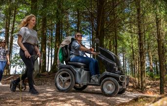 Group of women enjoying the trails at Haldon Forest Park with one person riding in an all terrain tramper