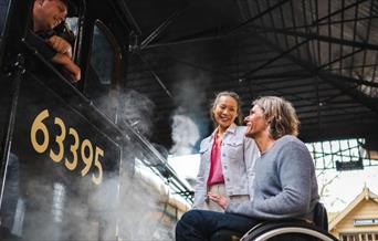 a couple talking to a driver at North Yorkshire Moors Railway, one on foot and one in a wheelchair