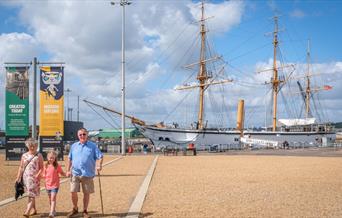 Family visiting The Historic Dockyard Chatham with a ship in the background