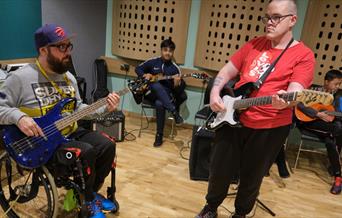 man in wheelchair playing guitar with a man standing playing guitar at Midlands Arts Centre