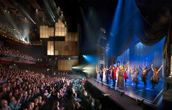 A performance taking place at Sadler’s Wells, with audience members applauding the actors on stage