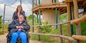 A person in a wheelchair being guided around the play area at Fairytale Farm