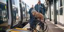 Person in a wheelchair boarding a GWR train via the ramp with station staff assisting