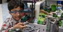 A child wearing goggles and playing with one of the exhibits at Coventry Transport Museum