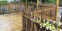 Decking and ramp leading up to Nutley Edge Cottages with a table and chairs set out and flowers lining the ramp