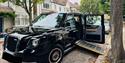 Taxi4Hire's black cab parked on the side of the road with the ramp out