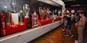 three boys looking at the cup Liverpool have won in the visitor experience room at LFC Stadium Tours & Experience