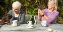 Two people enjoying coffee and cake with their dog at Cardinham Woods
