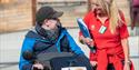 a person in an all terrain wheelchair talking to a member of staff at National Trust Pentire